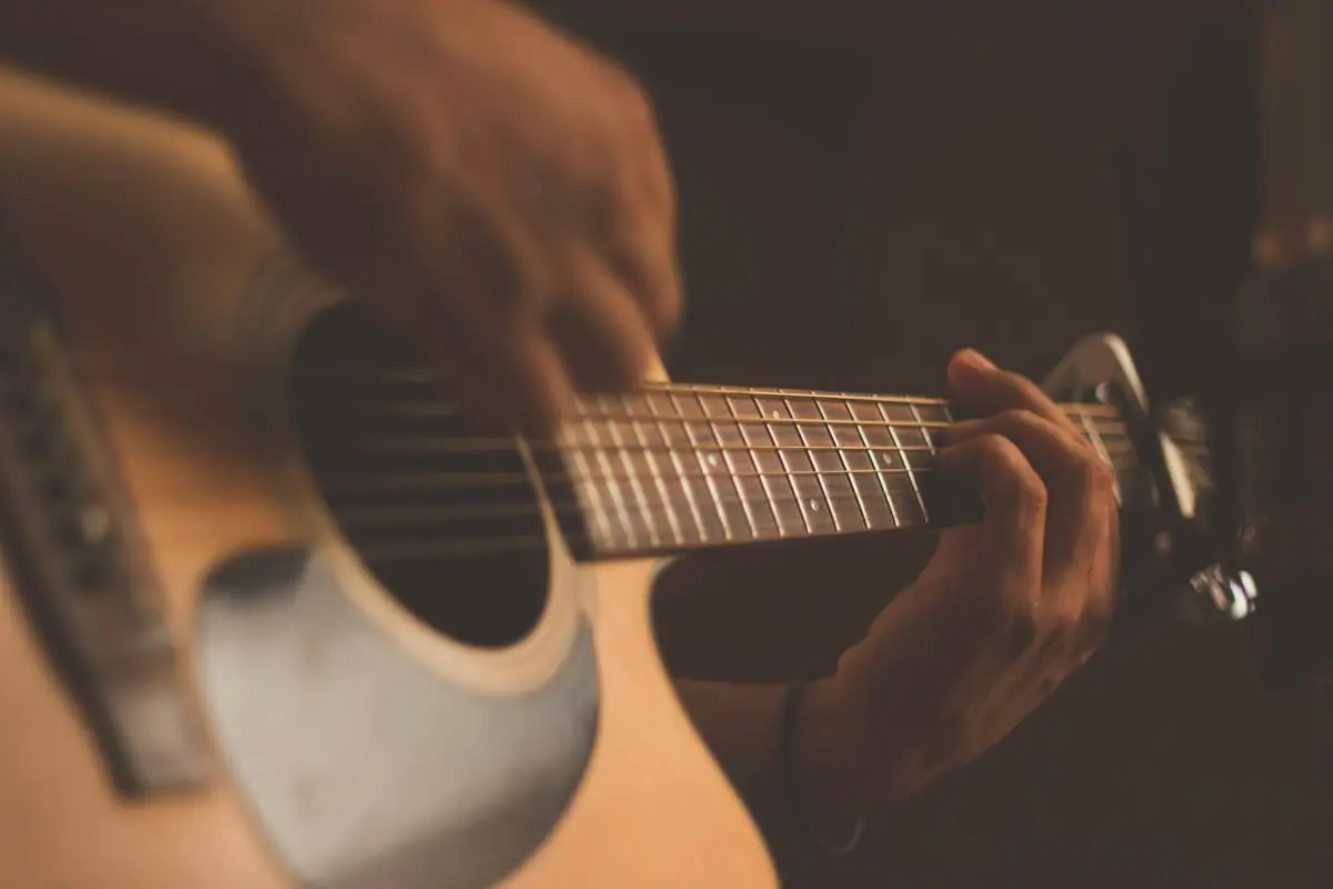 Akusztikus gitáron játszó zenész keze közelről